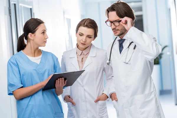 Médicos discutiendo diagnóstico con enfermera en clínica - foto de stock