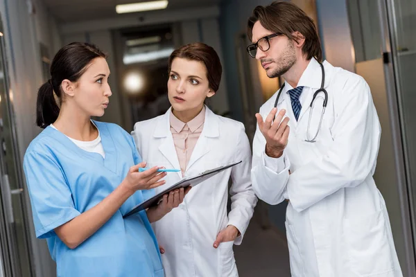 Médicos y enfermeras con portapapeles discutiendo diagnóstico - foto de stock