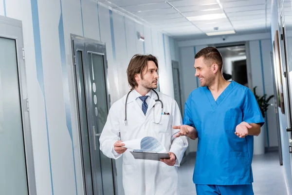 Medico con appunti che parla con l'infermiera in uniforme blu — Foto stock