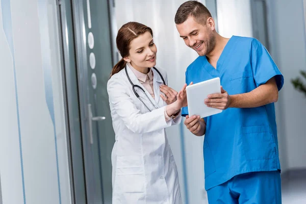 Sonrientes médicos jóvenes en uniforme usando tableta digital — Stock Photo