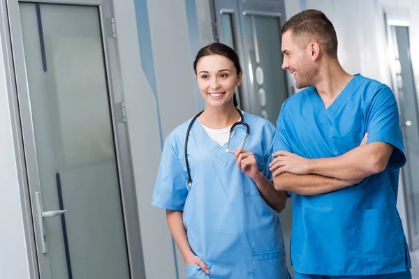 Médicos sonrientes en uniforme azul hablando en la sala - foto de stock