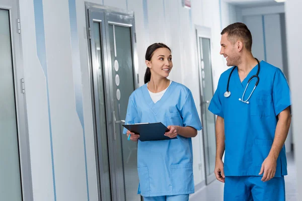 Doctors with clipboard and stethoscope talking and looking at each other — Stock Photo