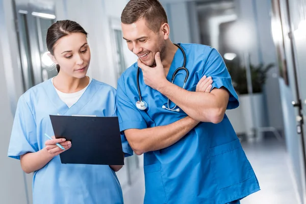 Médicos sonrientes con uniforme azul discutiendo el diagnóstico - foto de stock