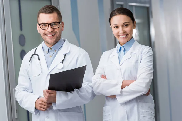 Médecins joyeux avec presse-papiers regardant la caméra avec le sourire — Photo de stock