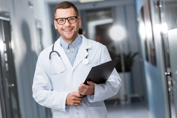 Médico sorridente em óculos segurando pasta preta — Fotografia de Stock