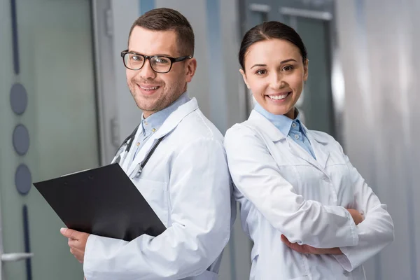 Médicos sonrientes con portapapeles mirando a la cámara - foto de stock