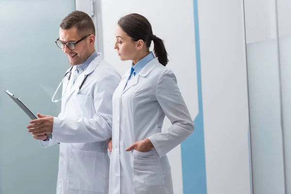 Médecins en manteaux blancs avec presse-papiers discutant du diagnostic — Photo de stock