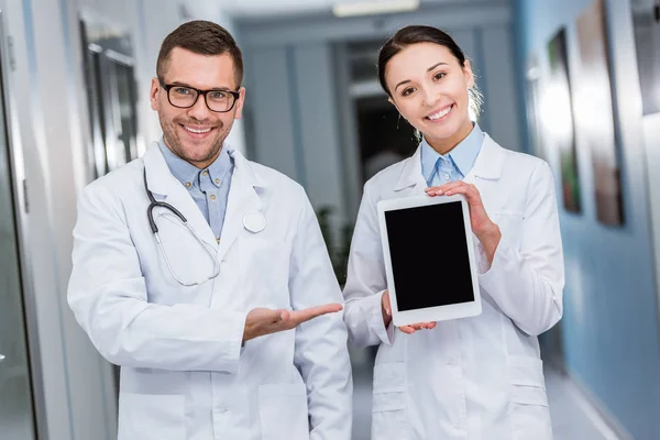 Médicos sonrientes sosteniendo tableta digital con pantalla en blanco - foto de stock