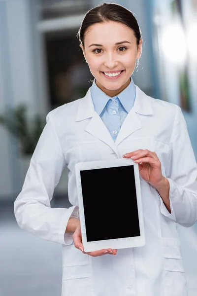 Laughing female doctor in white coat holding digital tablet with blank screen — Stock Photo