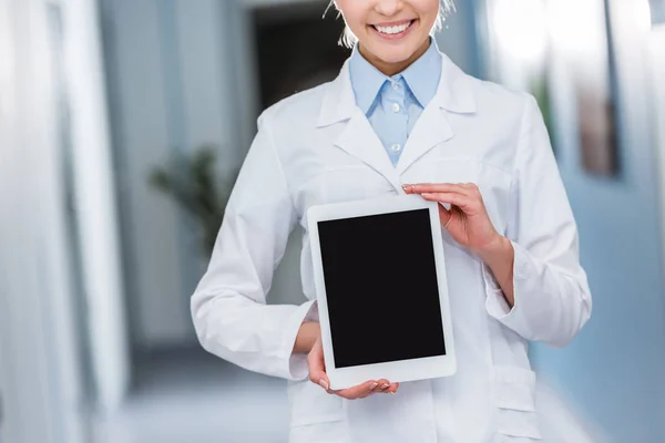 Vue recadrée d'un médecin souriant tenant une tablette numérique avec écran blanc — Stock Photo