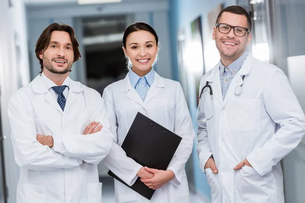 Médicos sonrientes con batas blancas mirando a la cámara - foto de stock