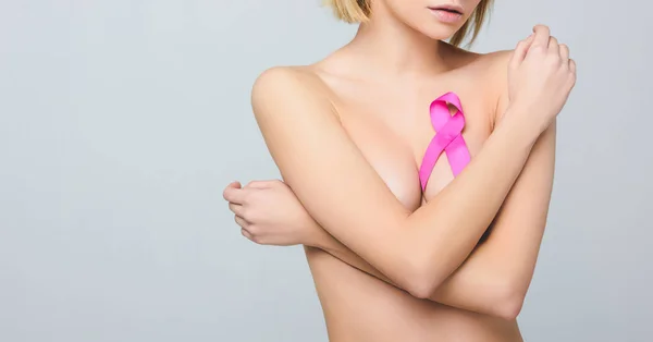 Обрезанный вид обнаженной женщины с розовой лентой осведомленности о раке молочной железы, изолированный на сером — стоковое фото