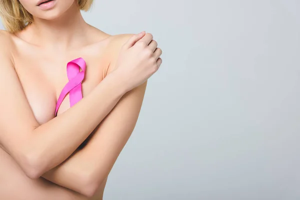 Abgeschnittene Ansicht einer jungen Frau mit rosa Brustkrebs-Bewusstseinsband, isoliert auf grau — Stockfoto