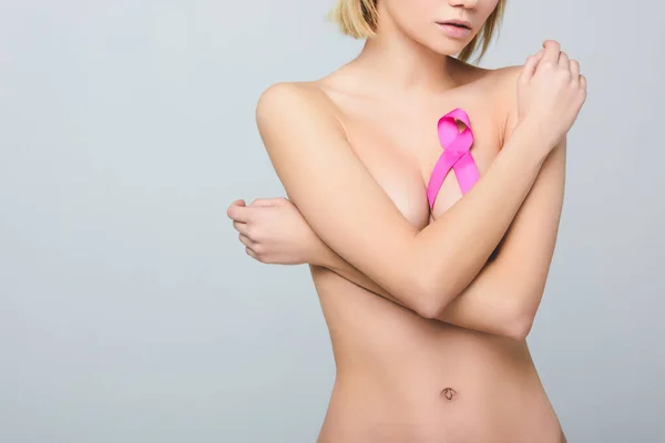 Cropped view of naked girl with pink breast cancer awareness ribbon, isolated on grey — Stock Photo