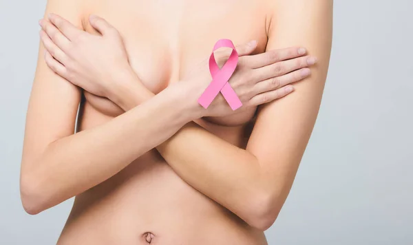 Vista a sezione centrale di donna nuda con nastro rosa di consapevolezza del cancro al seno, isolato su grigio — Foto stock