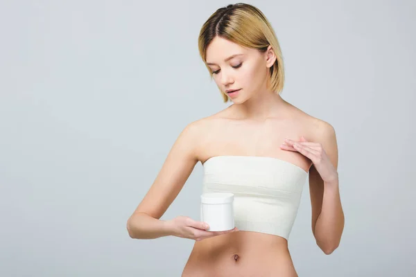 Belle femme en bandage sur le sein après une chirurgie plastique tenant récipient en plastique avec des médicaments, isolé sur gris — Photo de stock