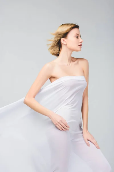 Elegante giovane donna nuda in posa in tessuto bianco, isolata su grigio — Foto stock