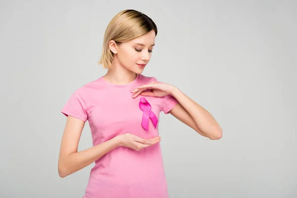 Cropped view of beautiful blonde woman posing in pink t-shirt with breast cancer awareness ribbon, isolated on grey — Stock Photo