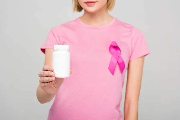 Vista cortada da menina em camiseta rosa com câncer de mama consciência fita segurando garrafa pílula, isolado em cinza — Fotografia de Stock