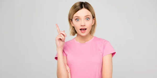 Shocked beautiful girl in pink t-shirt pointing up and having idea isolated on grey — Stock Photo