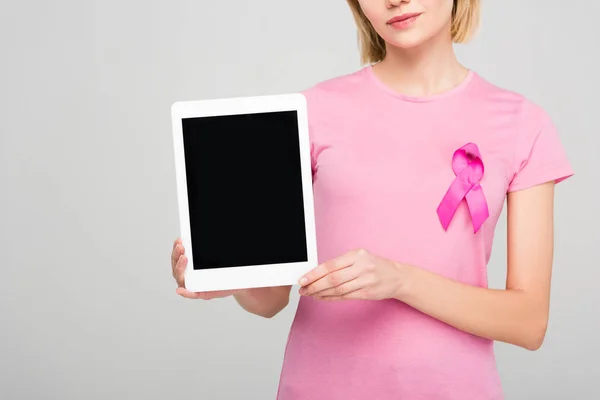 Vista recortada da menina em camiseta rosa com consciência de câncer de mama fita segurando tablet com tela em branco, isolado em cinza — Fotografia de Stock
