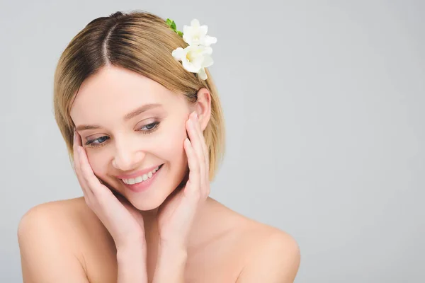 Jolie fille souriante avec une peau parfaite et des fleurs freesia dans les cheveux, isolé sur gris — Photo de stock