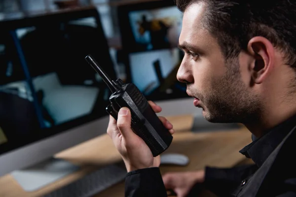 Selective focus of guard holding walkie-talkie at workspace — Stock Photo