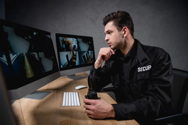 Concentarted guard looking at computer monitor and holding walkie-talkie — Stock Photo