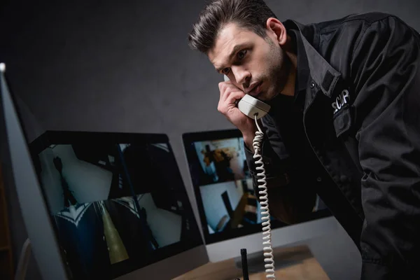 Garde en uniforme parler au téléphone et regarder l'écran d'ordinateur — Photo de stock