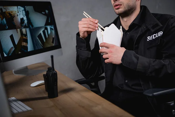 Cropped view of guard in uniform eating junk food — Stock Photo