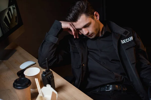 Guardia en uniforme negro durmiendo en el espacio de trabajo - foto de stock
