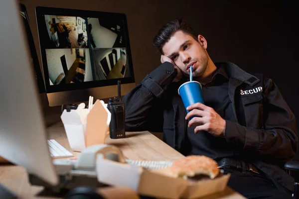Guapo guardia bebiendo de taza desechable en el lugar de trabajo - foto de stock
