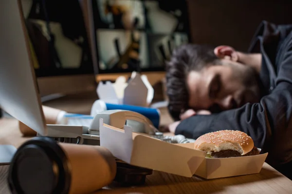 Selective focus of burger in paper box with sleeping guard at workplace on background — Stock Photo
