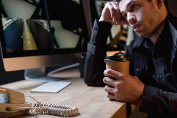 Garde fatigué tenant tasse en papier et regardant moniteur d'ordinateur — Photo de stock