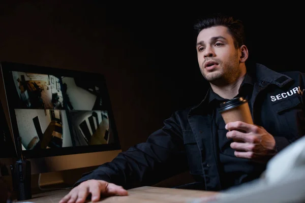 Guard holding paper cup and looking at computer monitor — Stock Photo