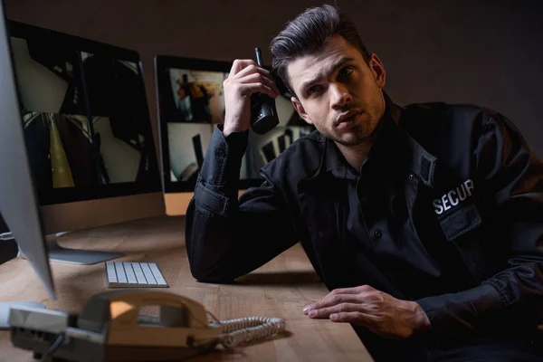 Gardien concentré en uniforme tenant talkie-walkie sur le lieu de travail — Photo de stock