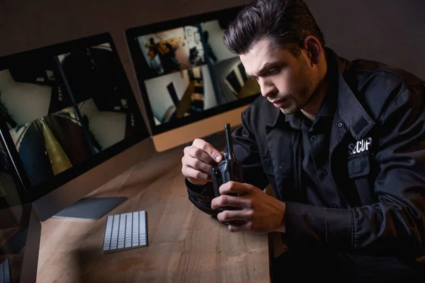 Guarda em uniforme preto segurando walkie-talkie no local de trabalho — Fotografia de Stock