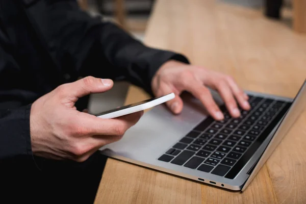 Cropped view of guard using smartphone and laptop — Stock Photo