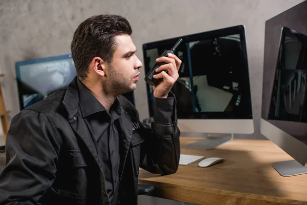 Garde en uniforme en utilisant walkie-talkie et en regardant l'écran de l'ordinateur — Photo de stock