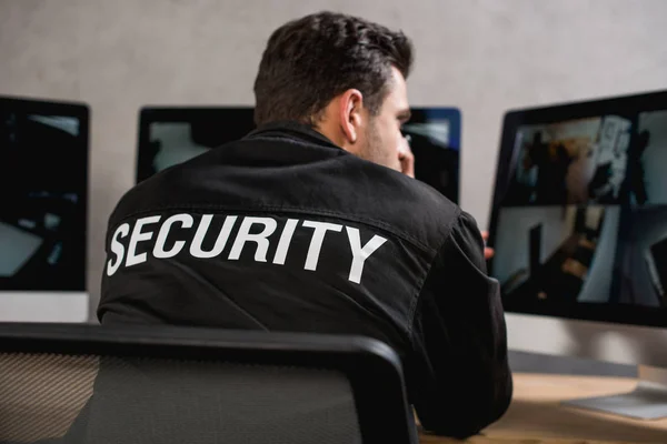Visão traseira de guarda em uniforme preto olhando para monitor de computador — Fotografia de Stock