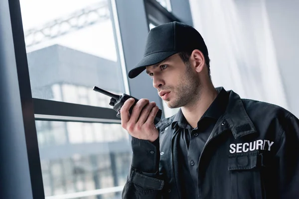 Cropped view of guard in uniform talking on walkie-talkie and looking away — Stock Photo