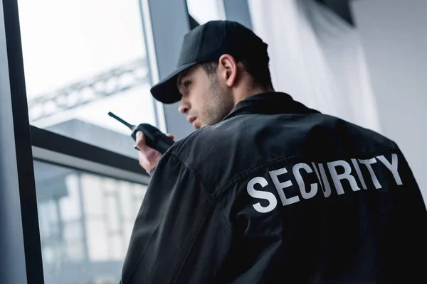 Rear view of guard in uniform talking on walkie-talkie — Stock Photo