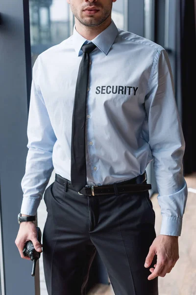 Vista parcial del guapo guardia en traje sosteniendo walkie-talkie - foto de stock