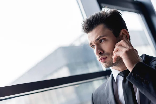 Focused handsome bodyguard in suit using earphone — Stock Photo