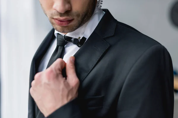 Cropped view of bodyguard in suit using microphone — Stock Photo