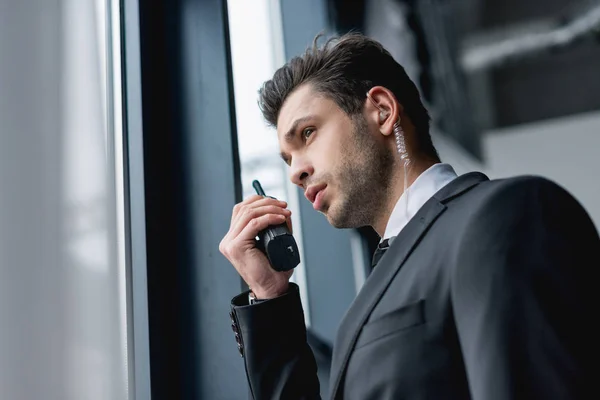 Guarda-costas bonito com fone de ouvido em terno preto usando walkie-talkie — Fotografia de Stock