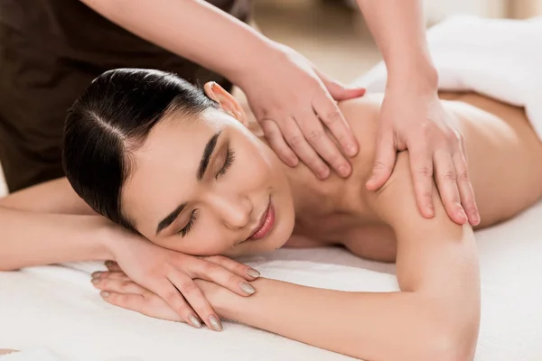 Vista parcial de masajista haciendo masaje de espalda a mujer atractiva - foto de stock