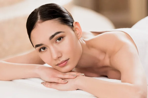 Hermosa mujer asiática descansando y mirando a la cámara en spa - foto de stock