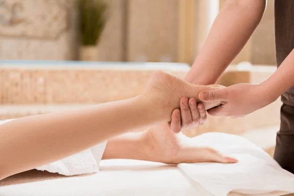 Vista cortada de massagista fazendo massagem nos pés para a mulher — Fotografia de Stock