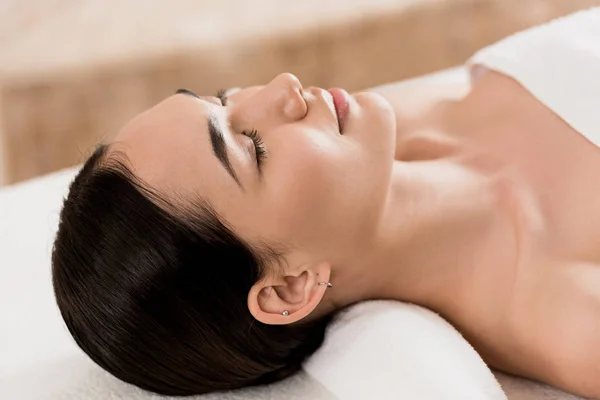 Attractive asian woman lying with closed eyes and relaxing at spa — Stock Photo